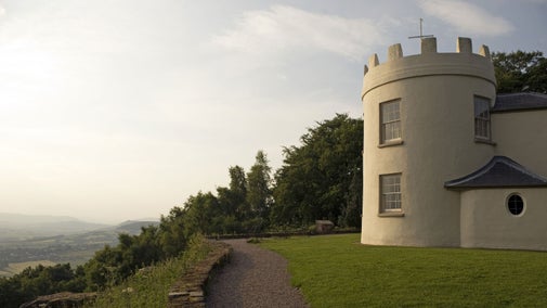 An exterior view of the the two-storey, circular, castellated Georgian banqueting house at the Kymin, the Monmouthshire countryside can be seen in the distance to the left of the picture.